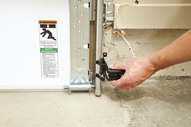 someone adjusting a sensor on a garage door